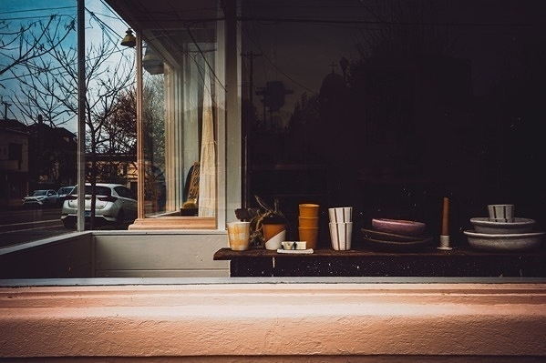 Bowls and cups stacked in a window on a wooden sill.