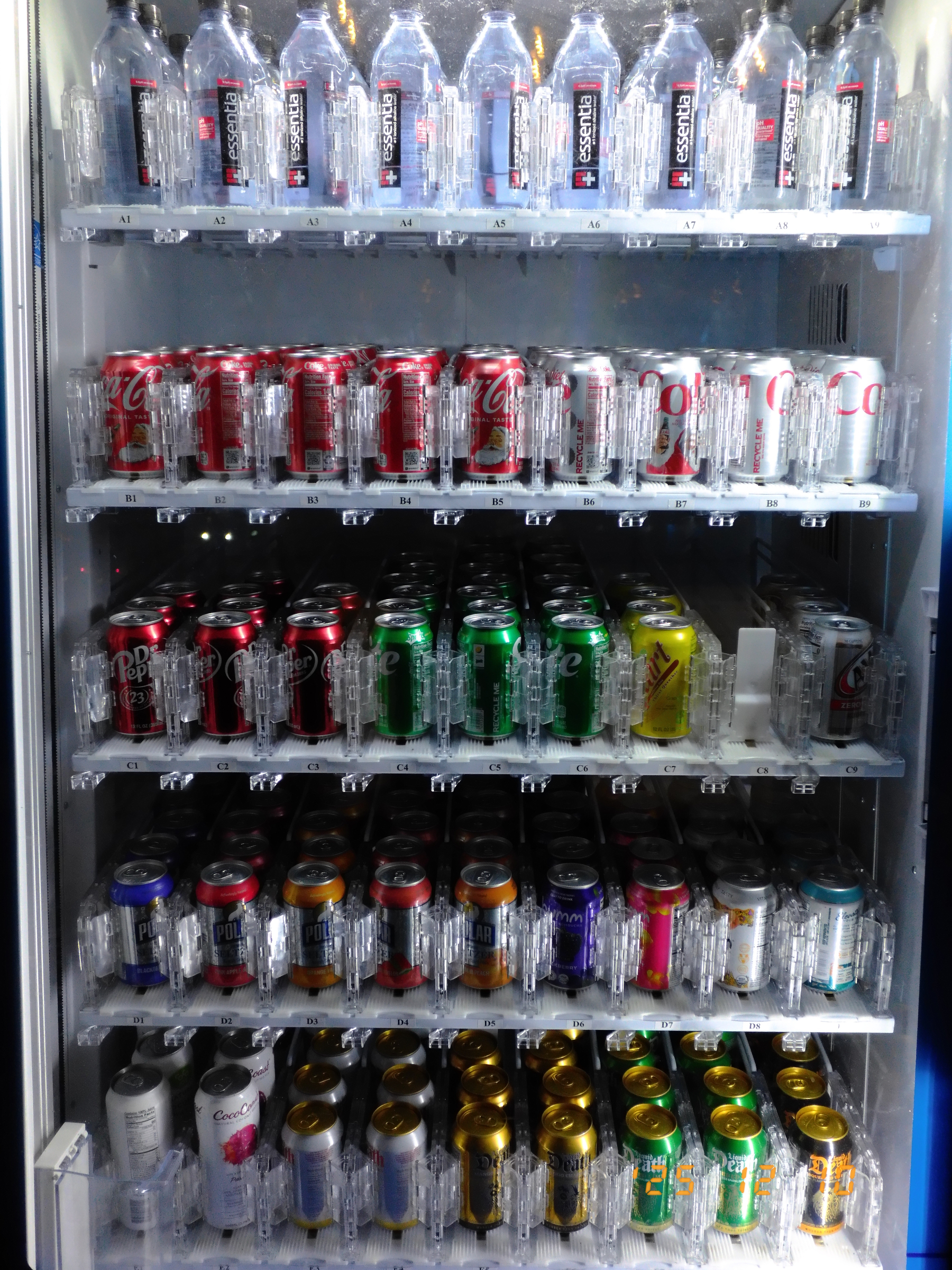 A vending machine is filled with various bottled waters and cans of beverages, including different types of soda.